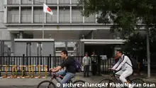 Men on bicycles go past the Japanese Embassy in Beijing, China, Wednesday, Sept. 30, 2015. China is holding two Japanese men on suspicion of spying, Japanese media reported Wednesday. Yoshihide Suga, the top Japanese government spokesman, told reporters that Japan does its utmost to protect citizens abroad, but that he would not discuss specific cases. (AP Photo/Ng Han Guan)