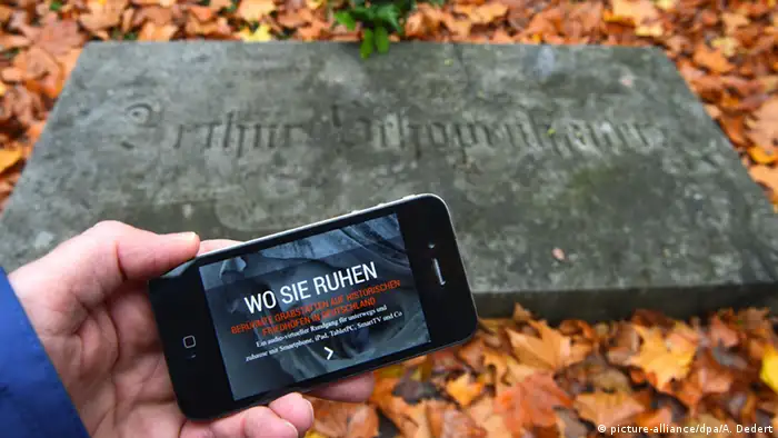 Ein Smartphone mit der App 'Wo sie ruhen' wird vor einen Grabstein gehalten (Foto: dpa/A. Dedert)