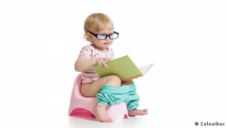 Baby Mädchen sitzt auf Nachttopf mit Buch (Colourbox)