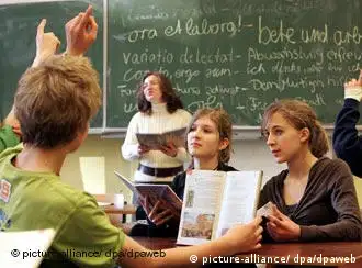 Vor einer mit lateinischen Sprichwörtern beschriebenen Tafel erteilt eine Lehrerin Unterricht (dpa)