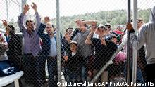 Migrants and refugees wait outside a fence of the Moria camp on the eastern Aegean island of Lesbos, Greece, Saturday Oct. 10, 2015. Greece¿s first ¿hotspot,¿ or migrant processing center, will open over the next 10 days, allowing migrants to be flown to other European Union countries, mostly of their preference, and have their asylum applications processed there, European Union officials say. (AP Photo/Antonis Pasvantis)