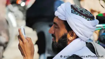 Man looking at his mobile phone in Pakistan (photo: picture alliance)
