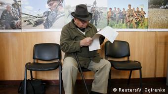 Чоловік вдивляється у виборчій бюлетень під час голосування на виборах до Київради в жовтні 2015 року 