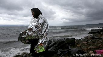 An Afghan refugee standds on a Greek beach after arriving on a raft