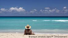 Ein Urlauber mit Strohhut blickt auf das türkisfarbene Meer und den blauen Himmel am Strand von Varadero auf Kuba, aufgenommen am 23.04.2013. Foto: Peter Zimmermann