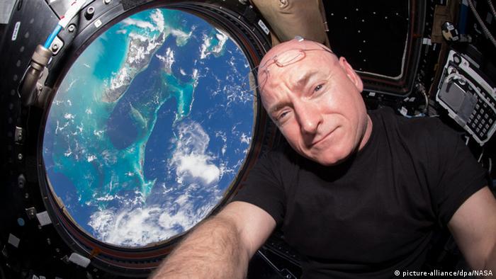 Scott Kelly auf der ISS neben einem Fenster mit Blick auf die Erde. (NASA)