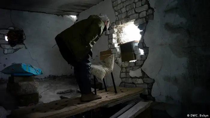 A Ukrainian marine peers at separatist positions through artillery damage in a former sanatorium