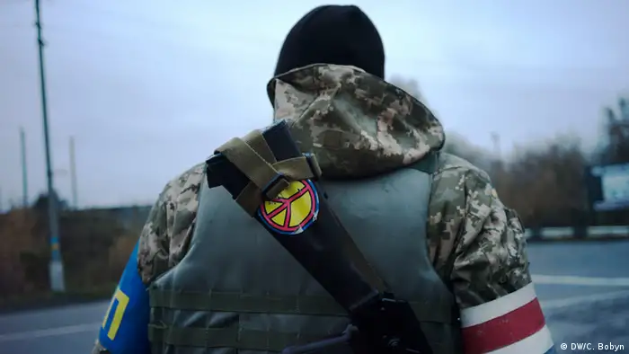A government soldier mans a checkpoint in Donetsk. A peace sticker is visible on his back