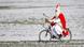 St. Nicholas with staff and mitre rides a bicycle across a snowy meadow, Germany (dpa)