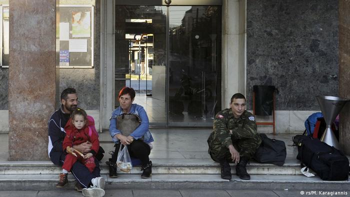 People wait outside a train station in Athens