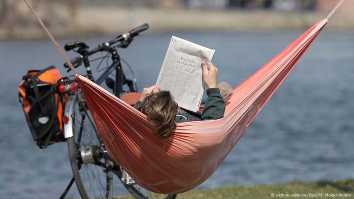 A man with a newspaper in a hammock, Copyright: picture-alliance/dpa/R.  Holschneider