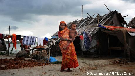 A woman stands with a child in one of Dhaka's 5,000 slums