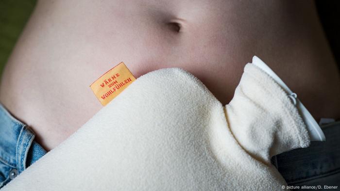 A hot-water bottle lies on a belly (Photo: picture alliance/D. Ebener)