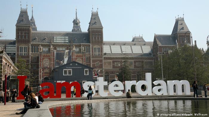 Das Rijksmuseum in Amsterdam, davor der Schriftzug Amsterdam in Großbuchstaben.