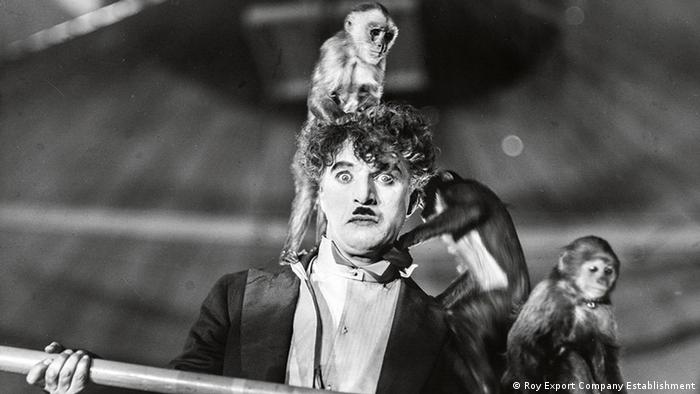 A still of Chaplin from a film with monkeys on his head.