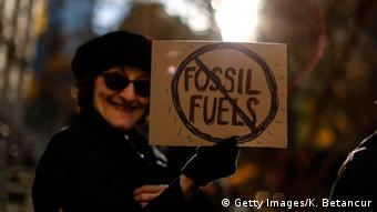 Woman holds anti-fossil fuels banner at global climate march in November 2015 in New York City