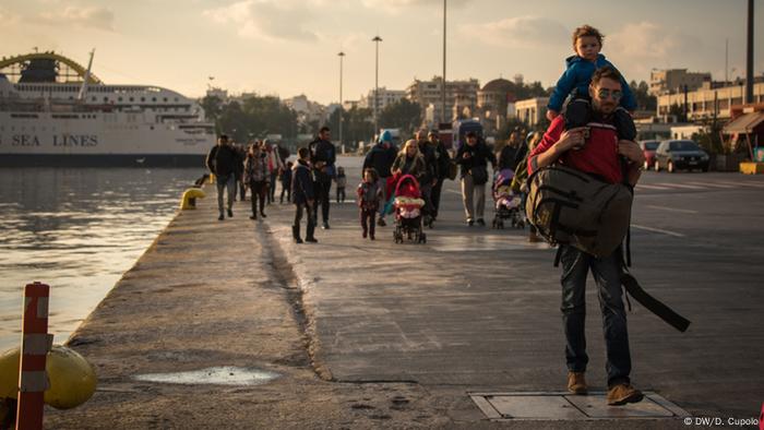 Adults and children walk along the pier in Piraeus, Greece