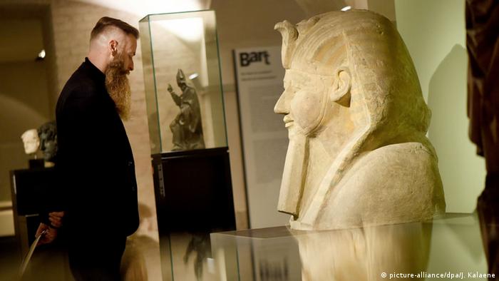 Ein Mann mit Bart betrachtet den Kopf der Königin Hatschepsut, ebenfalls mit Bart