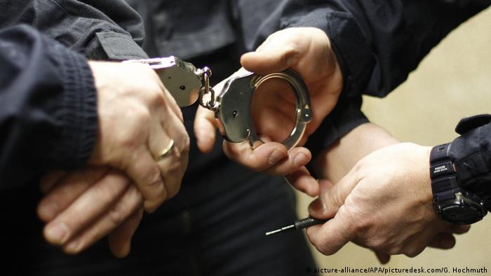 Полицейский надевает наручники задержанному