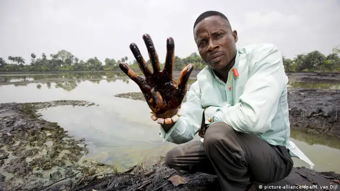 A man showing his hand dirty with oil after plunging it in the Niger Delta