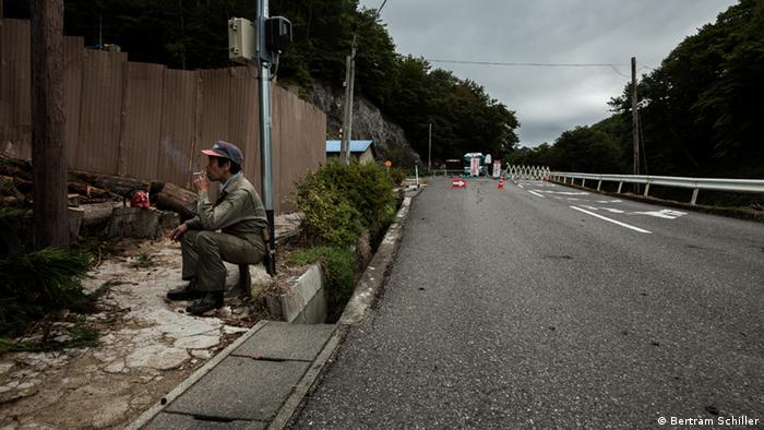 Rauchender Mann vor einer Straßensperre in das Sperrgebiet Fukushima (Foto: Bertram Schiller).