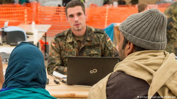 soldier with laptop, two refugees registering