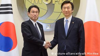 Der japanische Außenminister Fumio Kishida (links) am 28. Dezember 2015 gemeinsam mit seinem südkoreanischen Amtskollegen Yun Byung-Se in Seoul beim Handshake vor den Flaggen beider Länder (Foto: picture-alliance/dpa/K.Min-Hee)