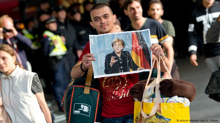 Refugees with photographs of Merkel at the railway station in Munich 