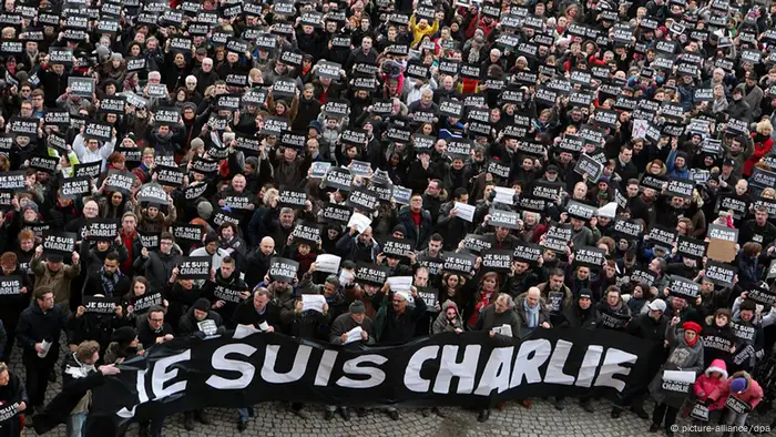 Protesters hold signs and a banner that say: Je suis Charlie — I am Charlie in French