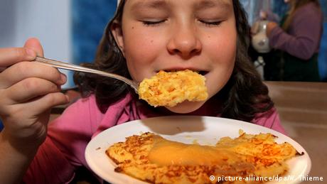 Ein Mädchen isst Kartoffelpuffer (picture-alliance/dpa/W. Thieme)