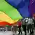 A group of people hold a large, rainbow flag