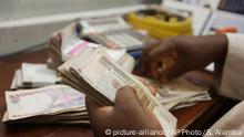In this photo taken Tuesday Oct. 20, 2015, a money changer counts Nigerian naira currency at a bureau de change, where a dollar buys 222 naira compared to the official rate of 198, in Lagos, Nigeria. The IMF is pressing Nigeria to further devalue its naira currency amid uncertainty over the political and economic outlook for Africa's biggest oil producer and economy. Analysts said there's disappointment that President Muhammadu Buhari's long-awaited Cabinet list includes no economic stars. The naira has lost 25 percent of its value in the past year and the stock market has plummeted because of political uncertainty and halved prices for oil that provides most government revenue.(AP Photo/Sunday Alamba) Copyright: picture-alliance/AP Photo/S. Alamba