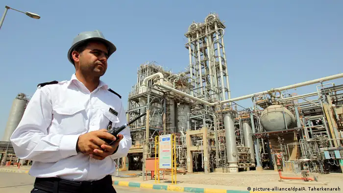 An Iranian oil worker in front of a refinery