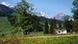 A scene in Bavaria with a cottage in a blooming meadow and mountains in the distance A scene in Bavaria with a cottage in a blooming meadow and mountains in the distance