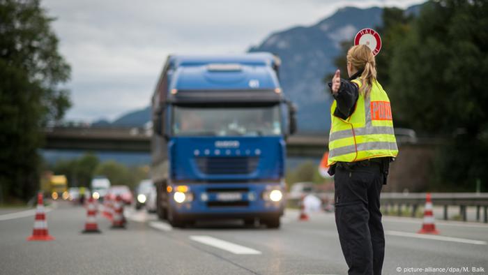 Auf einer Autobahn winkt eine Polizistin ein Fahrzeug in eine Grenzkontrollstelle
