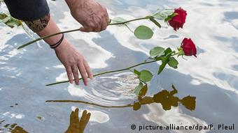 Zwei Leute legen Rosen ins Wasser (Foto: Patrick Pleul/dpa)
