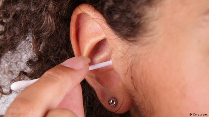 Woman cleaning her ear with a cotton ear bud