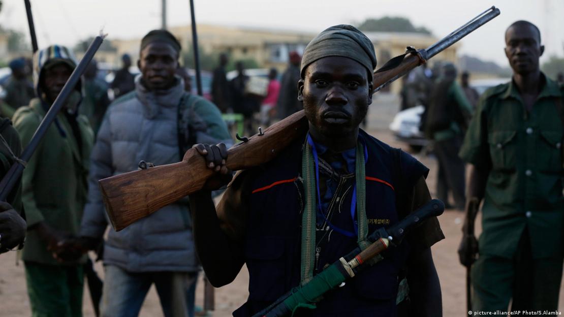 Men bearing homemade guns and other weapons pose for a photograph. Men bearing homemade guns and other weapons pose for a photograph.