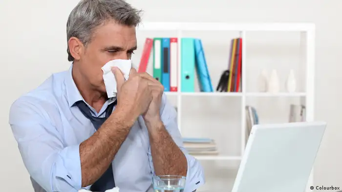 Erkältung Büro Mann mit Taschentuch Nase putzen