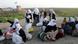 Elf jesidische Frauen sitzen mit Sack und Pck auf einer verlassenen Landstraße. Im Hintergrund weht eine jesidische Flagge. (Foto: Imago) Elf jesidische Frauen sitzen mit Sack und Pck auf einer verlassenen Landstraße. Im Hintergrund weht eine jesidische Flagge. (Foto: Imago)