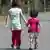 Zwei Flüchtlingskinder gehen Hand in Hand eine Straße entlang (Foto: DPA)