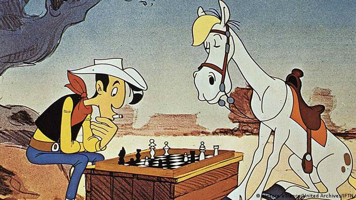 Lucky Luke spielt mit seinem Pferd Jolly Jumper Schach. 