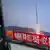 A person walks past a TV screen broadcasting a news report on North Korea's long range rocket launch