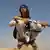 Ein Kindersoldat hockt mit einer Kalaschnikow beobachtend in Afghanistan. Foto: picture alliance/Tone Koene