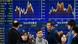 Pedestrians stand before a foreign currency indicator board in Tokyo, Japan. Pedestrians stand before a foreign currency indicator board in Tokyo, Japan.