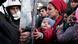 A woman holds a baby as migrants and refugees stand facing Greek police A woman holds a baby as migrants and refugees stand facing Greek police