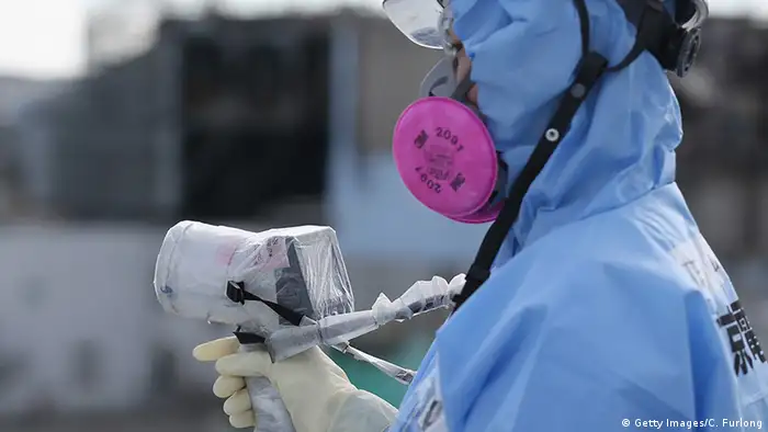 Japan Okuma Fukushima Daiichi Schutzanzug employee uses a a radiation dosage minitor