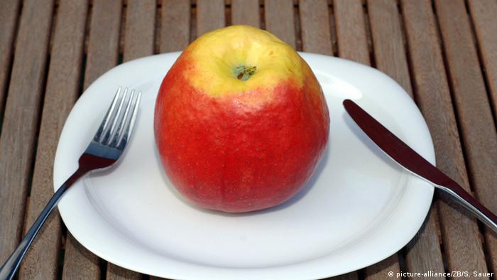 Ein Apfel liegt mit Besteck auf einem Teller (picture-alliance/ZB/S. Sauer)