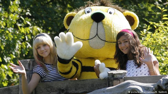 Two girls pose with a person dressed as Little Tiger.