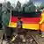Children in rain gear hold up a German flag over train tracks in Idomeni